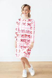 Bow La La Long Sleeve Pocket Twirl Dress on a smiling girl with pink bow print and twirl skirt.