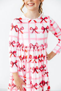 Bow La La Long Sleeve Pocket Twirl Dress on a girl, pink plaid with red bows and twirl skirt.