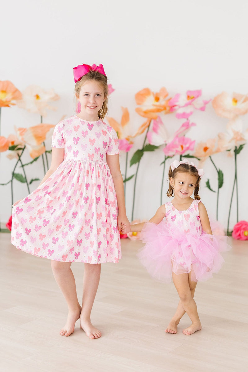 Girl twirling in the Bow Beauty S/S Pocket Twirl Dress by Mila & Rose ®, showcasing its playful design and vibrant colors.