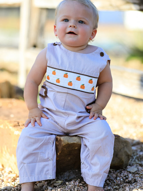 Baby boy wearing a fall pumpkin-embroidered smocked romper with lavender gingham and brown trim.