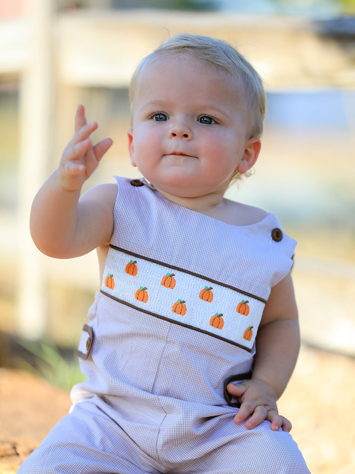 Baby boy in lavender check romper with pumpkin embroidery and brown trim, perfect for fall Halloween and Thanksgiving.
