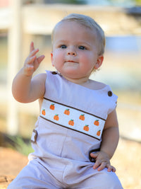 Baby boy in lavender check romper with pumpkin embroidery and brown trim, perfect for fall Halloween and Thanksgiving.