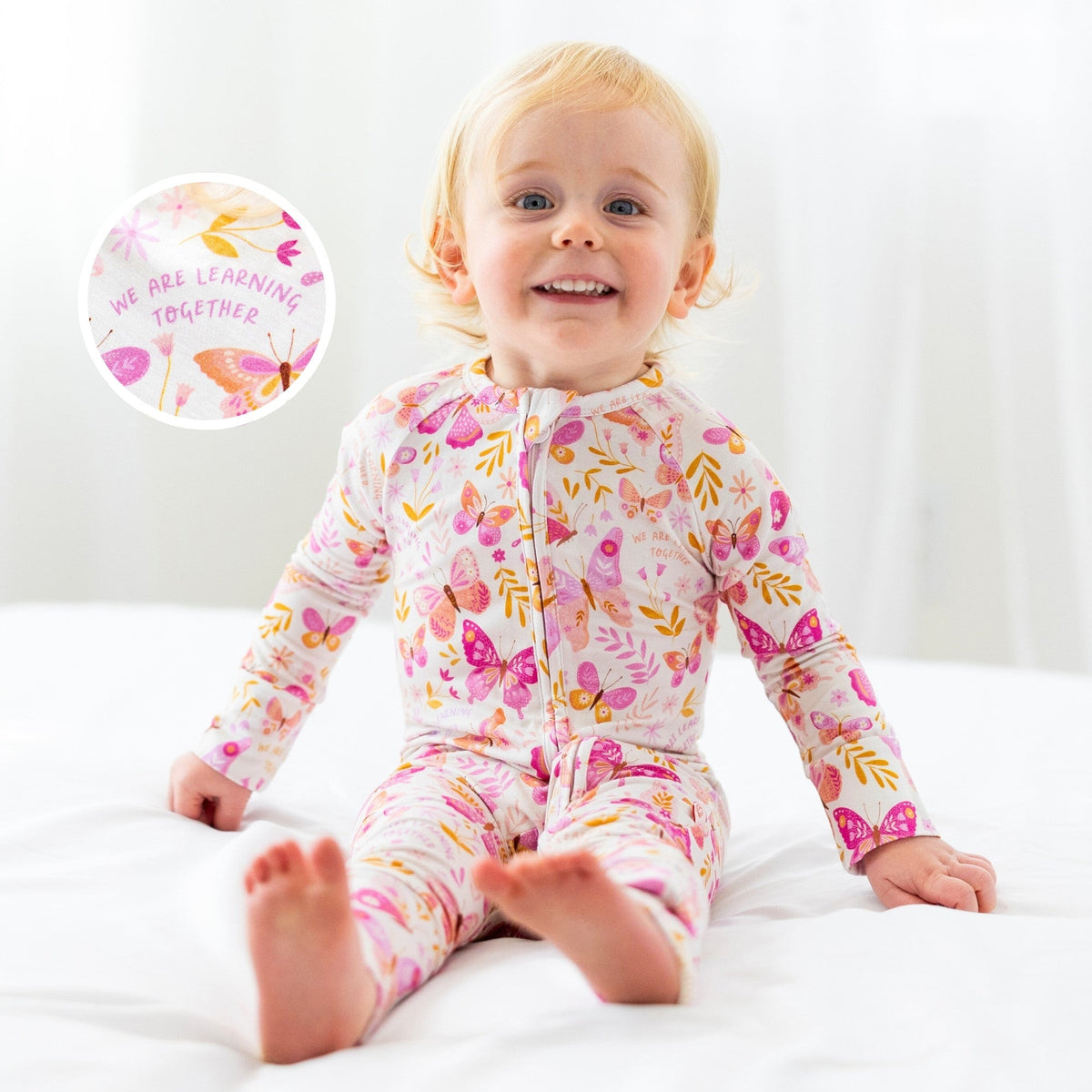 Smiling toddler in The Second-Skin Convertible Romper, butterfly print, zip front, made with soft viscose from bamboo.