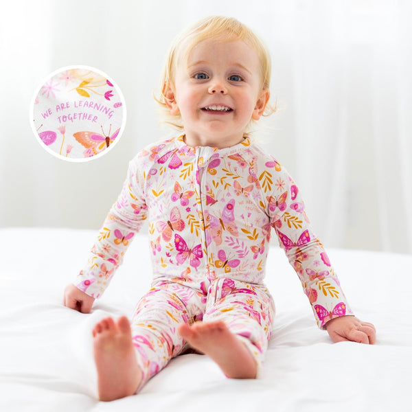 Smiling toddler in The Second-Skin Convertible Romper, butterfly print, zip front, made with soft viscose from bamboo.
