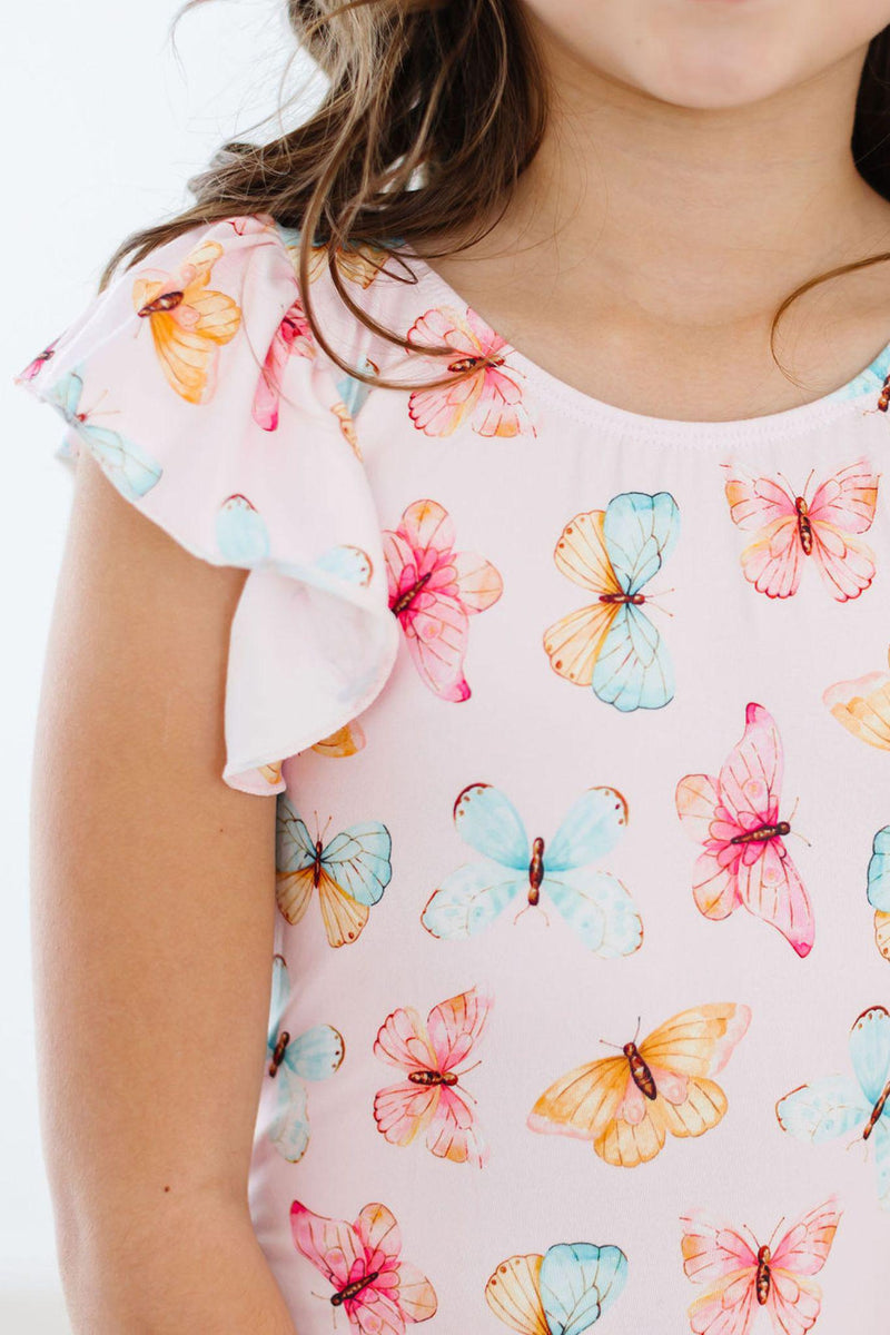 Close-up of a child wearing the Butterfly Kisses Short Sleeve Flutter Sleeve Leotard, showcasing delicate flutter sleeves and a vibrant butterfly design, ideal for dance class.