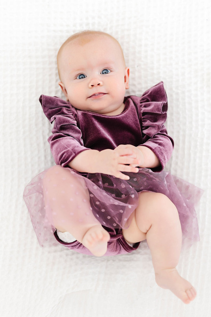 Happy baby wearing Amethyst Velvet Baby Tutu Bodysuit, showing off the cute ruffles and polka dot tulle skirt, ideal for twirling and play.