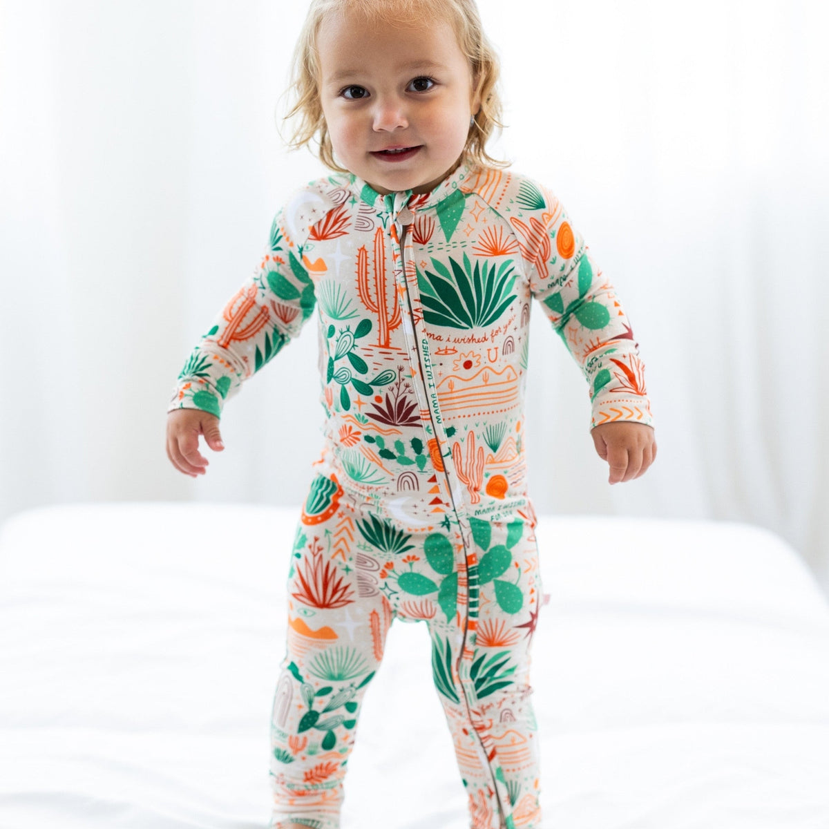 Toddler in Desert Cactus beige Second-Skin Convertible Romper with cactus print and zip.