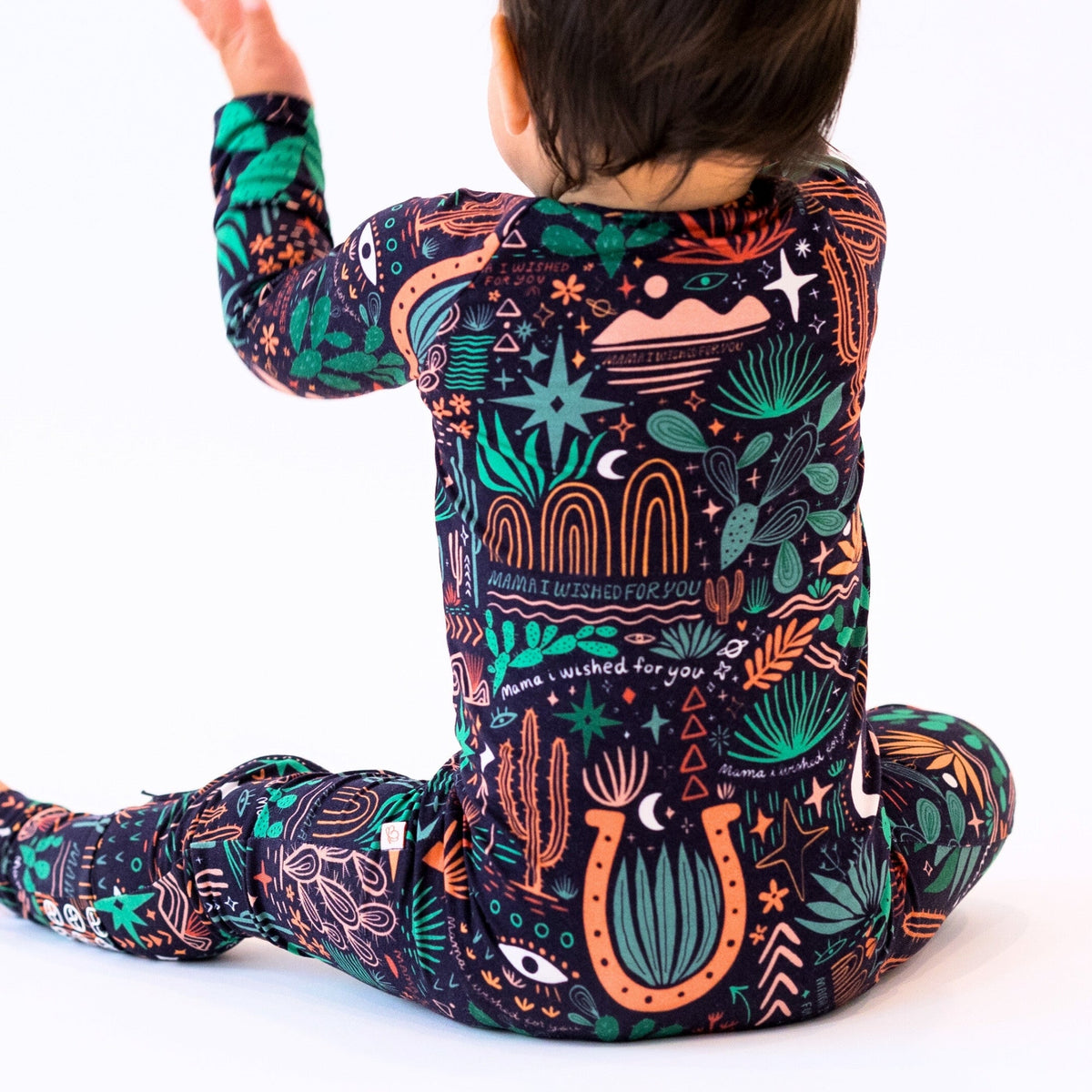 Child wearing The Second-Skin Convertible Romper Desert Cactus Midnight with a vibrant botanical print.