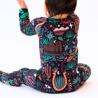 Child wearing The Second-Skin Convertible Romper Desert Cactus Midnight with a vibrant botanical print.
