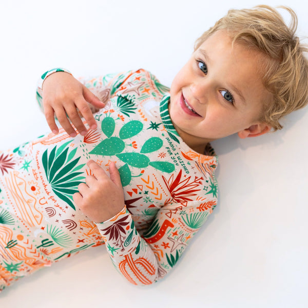 Child in The Second-Skin 2-Piece Long Sleeve Pajama, Desert Cactus beige with cactus print.
