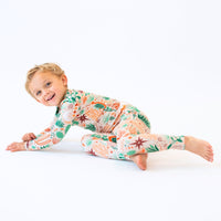 Happy child in Desert Cactus beige two-piece long-sleeve pajama with colorful hand-drawn print.