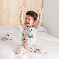 Joyful child wearing The Second-Skin 2-Piece Short Sleeve Pajama in Desert Cactus beige, arms raised.