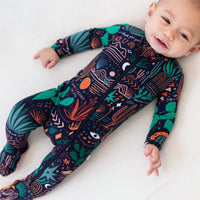 Baby wearing The Second-Skin Footie: Desert Cactus (Midnight) with zip, hand-drawn print on cozy one-piece.