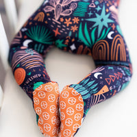 The Second-Skin Footie Desert Cactus (Midnight) on baby; navy zippered with teal cacti, stars, moons, orange swirls.