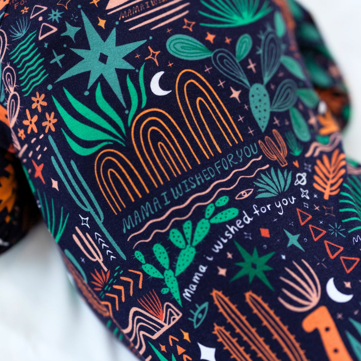 The Second-Skin Convertible Romper in Desert Cactus Midnight fabric with neon teal and orange print.