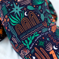The Second-Skin Convertible Romper in Desert Cactus Midnight fabric with neon teal and orange print.