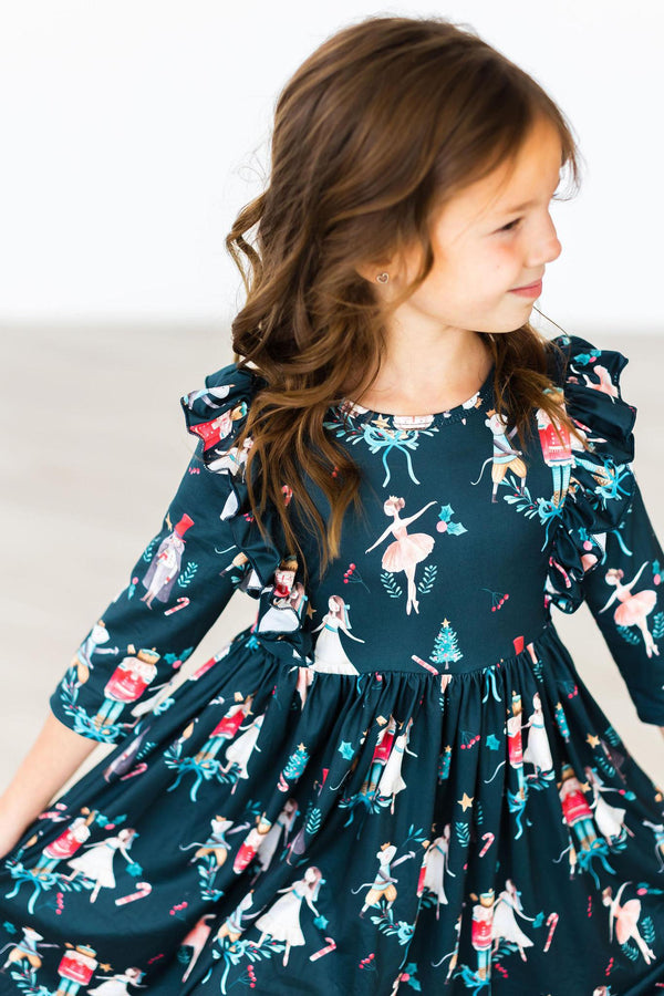 Child wearing a dark green Christmas ballet ruffle twirl dress featuring nutcracker and ballerina prints with 3/4 sleeves.
