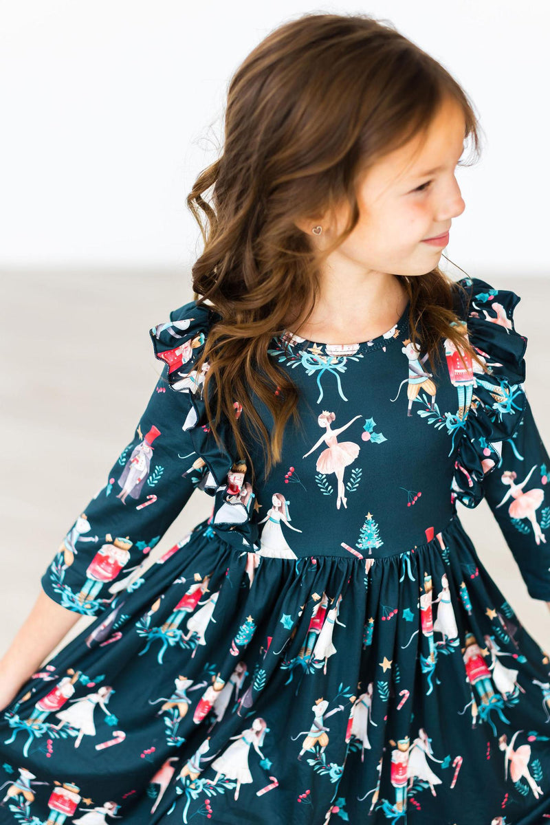 Child wearing a dark green Christmas ballet ruffle twirl dress featuring nutcracker and ballerina prints with 3/4 sleeves.