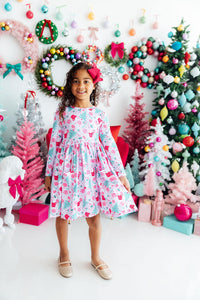 Girl wearing Cocoa Kisses Long Sleeve Pocket Twirl Dress amid festive Christmas decorations.