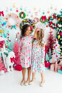 Two girls wear Cocoa Kisses Long Sleeve Pocket Twirl Dress with pastel print, scoop back and full twirl skirt.