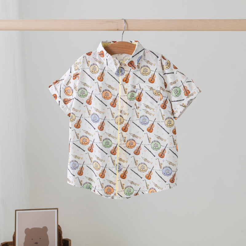 Short-sleeve shirt with musical instrument pattern on a hanger against a plain background