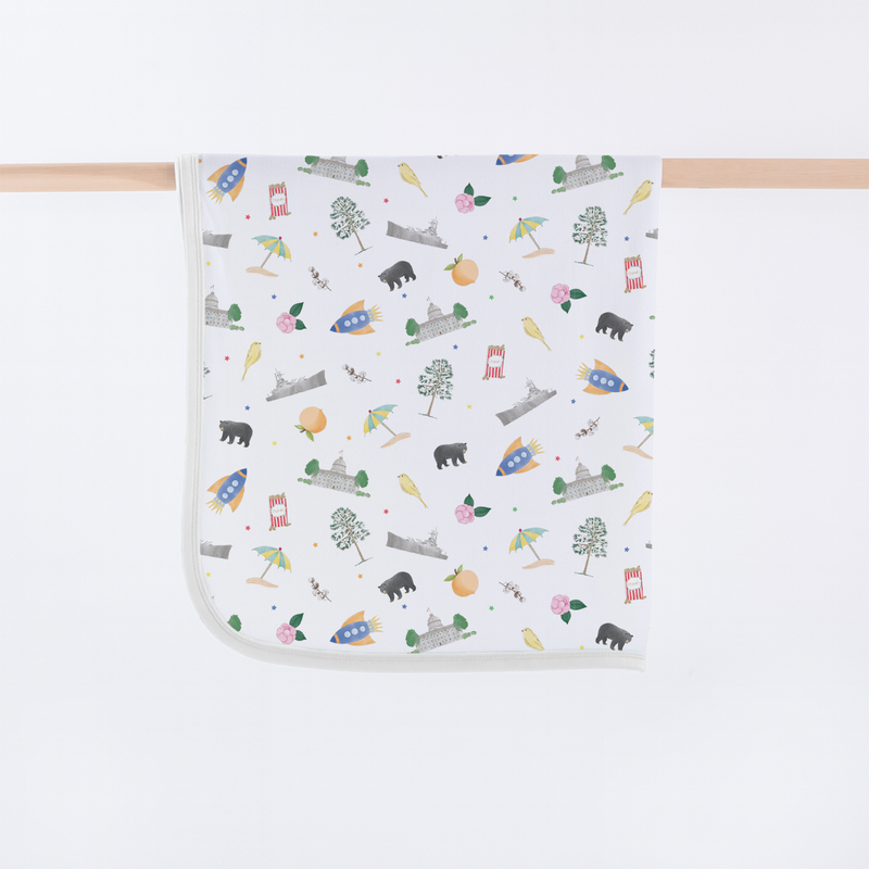 Alabama Kids Organic Cotton Baby Blanket with Alabama motifs: peanuts, cotton blooms, honeybees, peaches, landmarks.