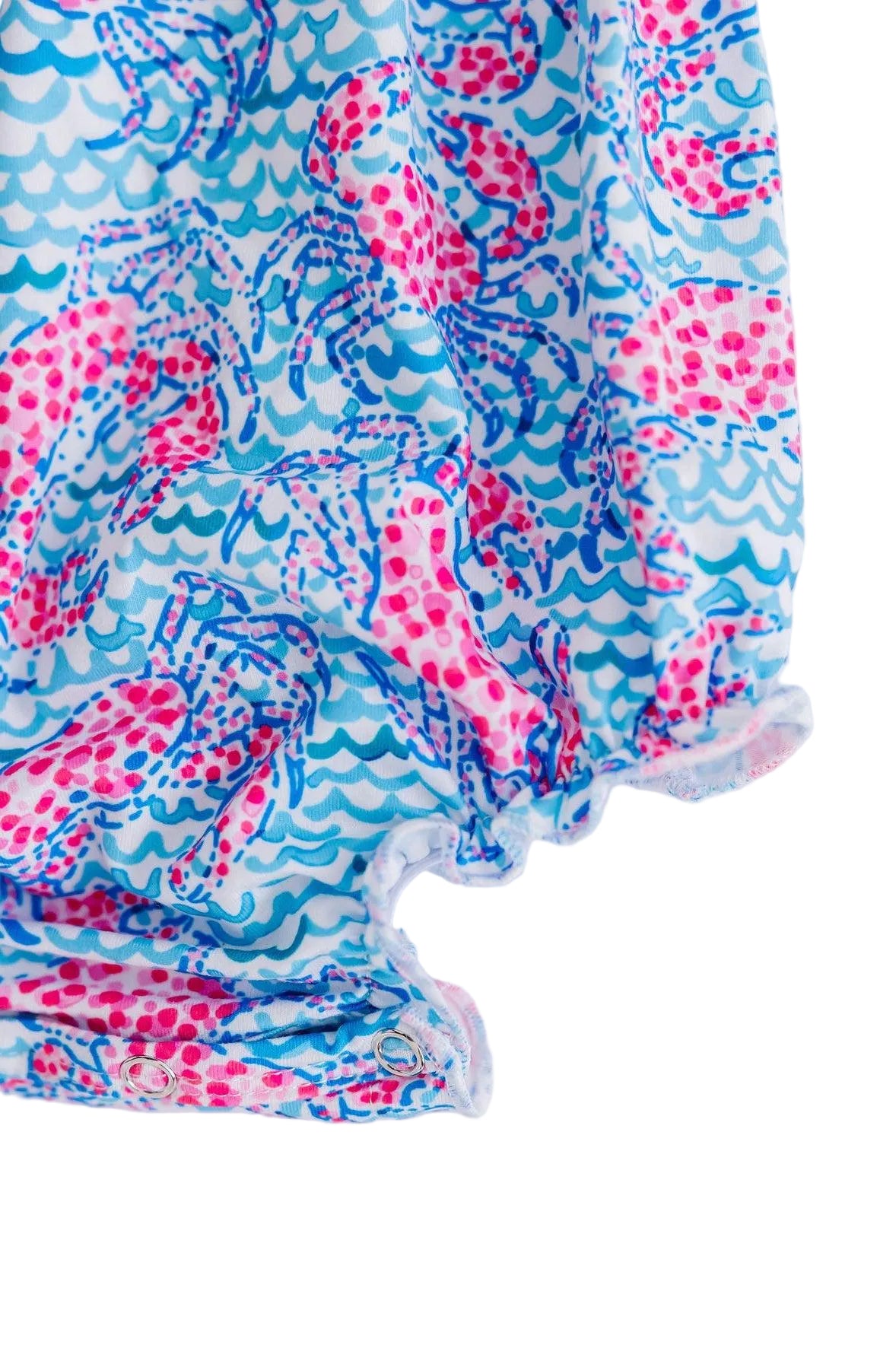 Crab Walk Ruffle Cross Back Romper in a blue-pink print with crisscross back straps and diaper snaps.