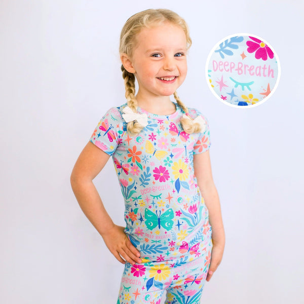 Smiling girl in a light-blue floral two-piece pajama set; Deep Breath round logo sticker visible.