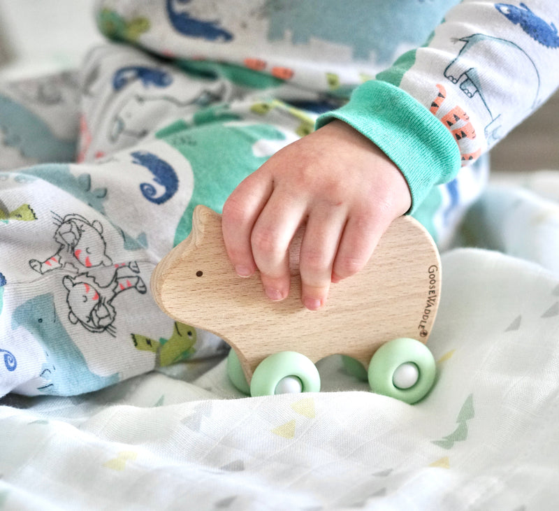Child playing with the Silicone + Wood Teether with Wheels, demonstrating its engaging design and comfort for little hands during teething.