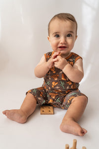 Smiling baby in organic bamboo shorty romper with leg snaps and wood toy