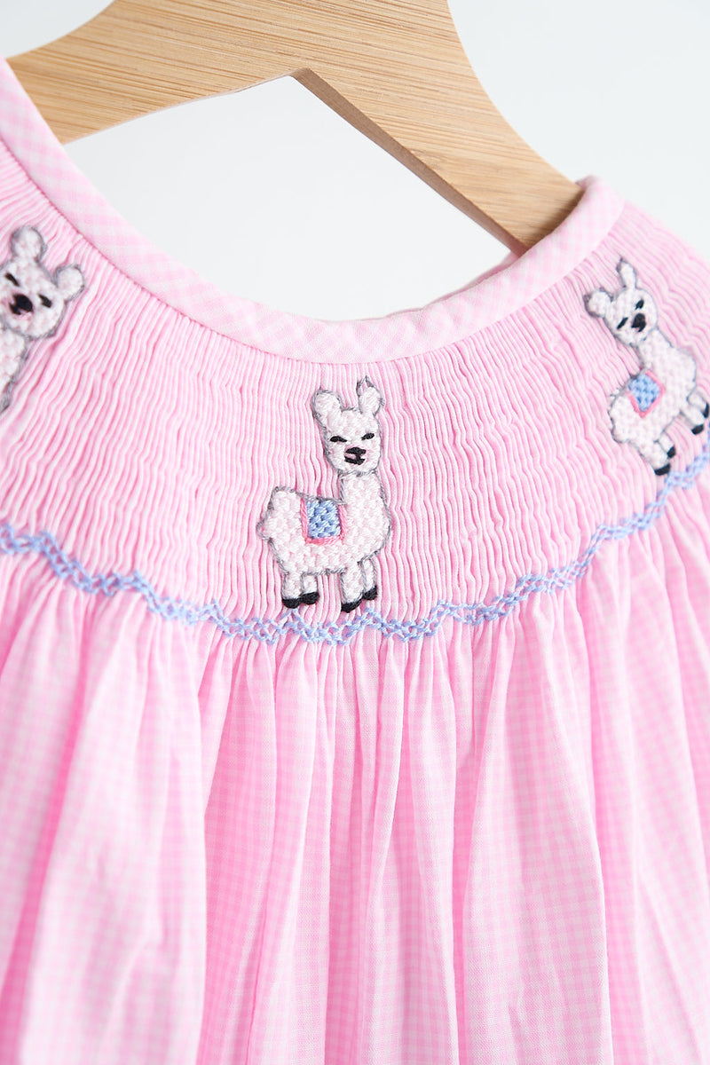 Pink alpaca hand smocked gingham girl romper with blue trim detail on soft checkered fabric