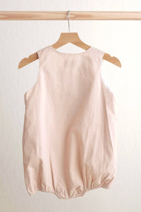 Pink sleeveless dress on a wooden hanger against a white background