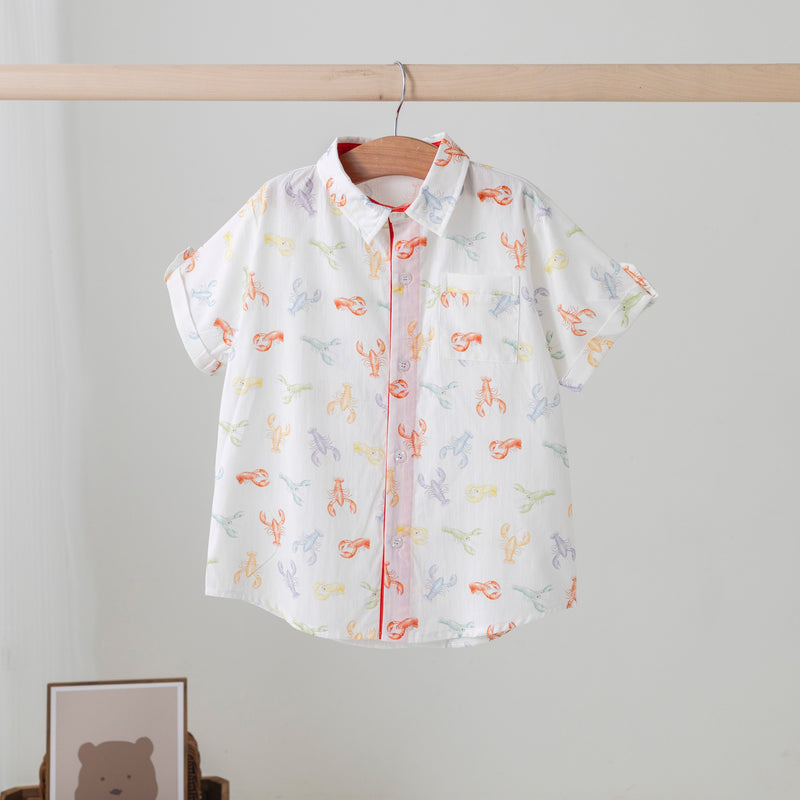 Short-sleeve shirt with animal pattern hanging on a rack against a plain wall.
