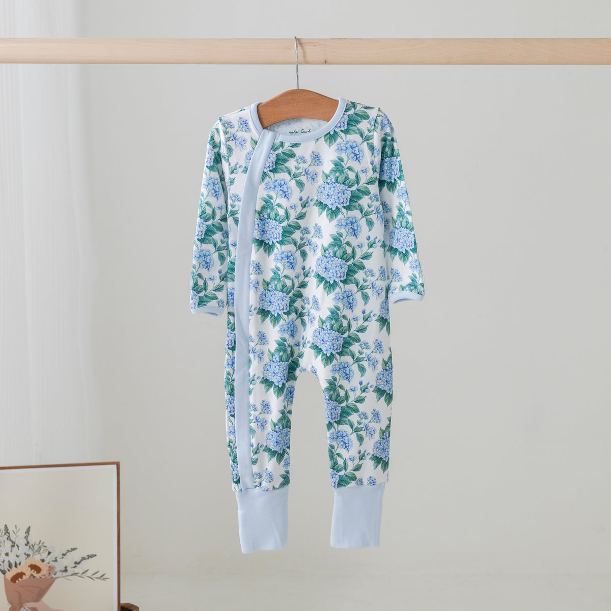 Hydrangea Heaven organic cotton kids pajama set with blue hydrangea print on a wooden hanger