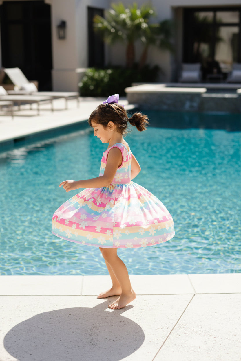 little girl twirling around in a dress by the pool