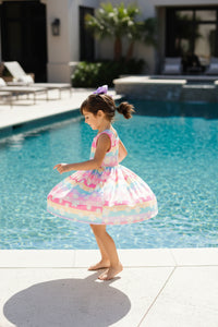 little girl twirling around in a dress by the pool
