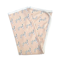 Folded pink organic cotton baby blanket featuring a playful black and white Dalmatian print with white ribbed edges.