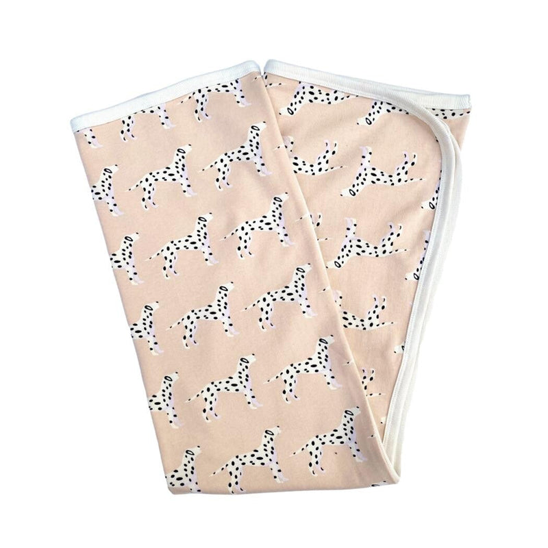 Folded pink organic cotton baby blanket featuring a playful black and white Dalmatian print with white ribbed edges.