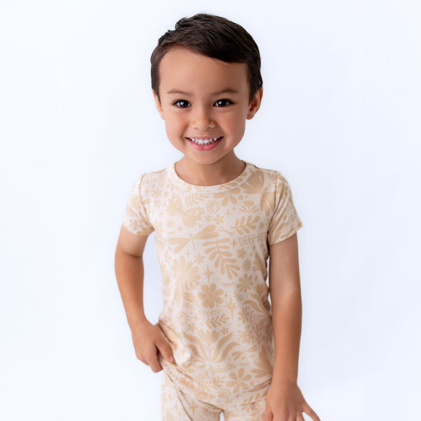 The Second-Skin 2-Piece Short Sleeve Pajama in beige worn by a smiling child.