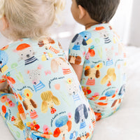 Two kids wear Mindful Doggos The Second-Skin 2-Piece Short Sleeve Pajama with hand-drawn animal prints.