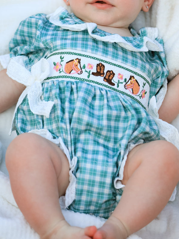 Mint plaid bubble romper with embroidered horses, cowboy boots, and white lace trim. Western-inspired baby outfit with puff sleeves and bow accents.