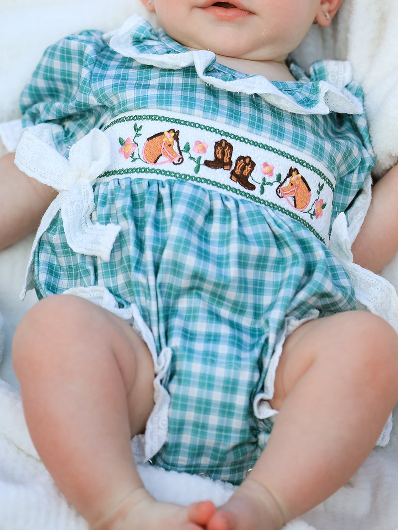 Mint plaid bubble romper with embroidered horses, cowboy boots, and white lace trim. Western-inspired baby outfit with puff sleeves and bow accents.