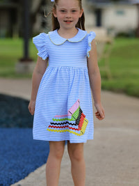Girl in light-blue striped dress with ruffle sleeves and petal collar, featuring colorful crayon applique.