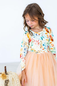 Girl wearing fall watercolors long sleeve tutu dress with peach skirt and leaf print top for play or special occasions.