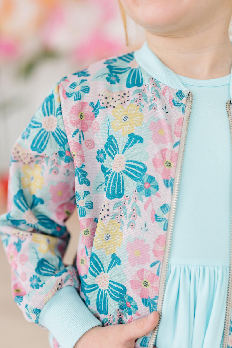 Charming child showcasing the Floral Garden Shimmer Jacket from Mila & Rose, vibrant floral design bringing a playful twist to stylish layering.