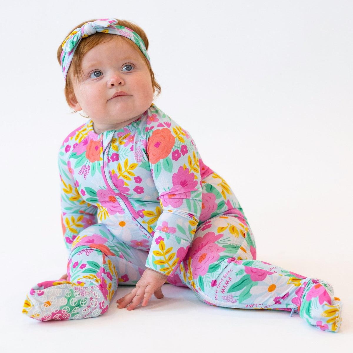 Baby in The Second-Skin Convertible Romper in Flower Power floral print with coordinating headwrap.