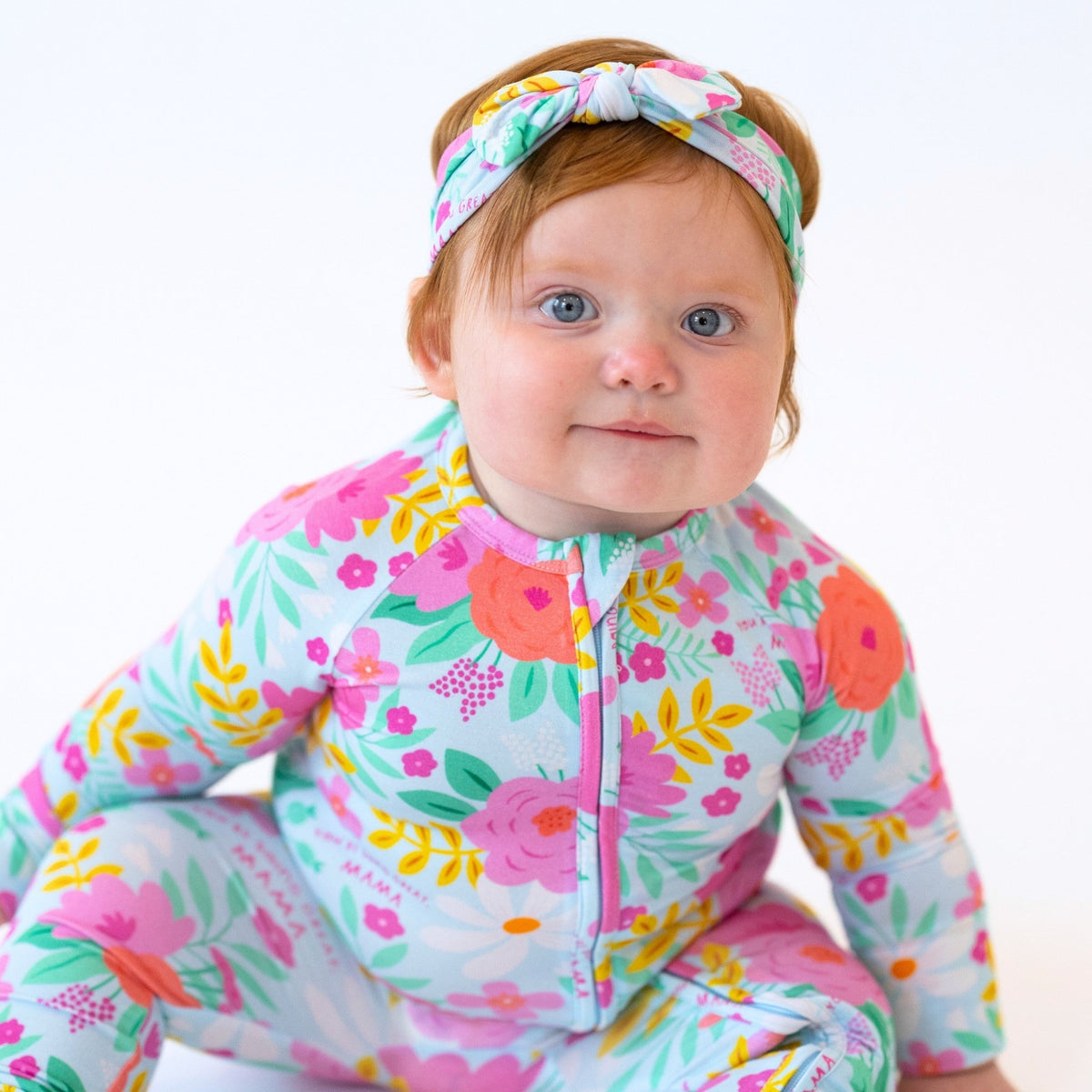 Baby wearing The Second-Skin Convertible Romper in Flower Power with a matching floral headband.