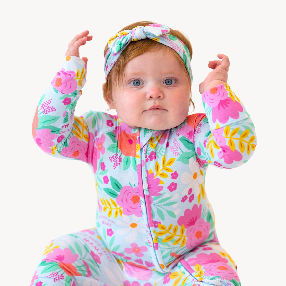 The Second-Skin Convertible Romper | Flower Power zippered outfit on a baby in a bright floral print with headwrap.