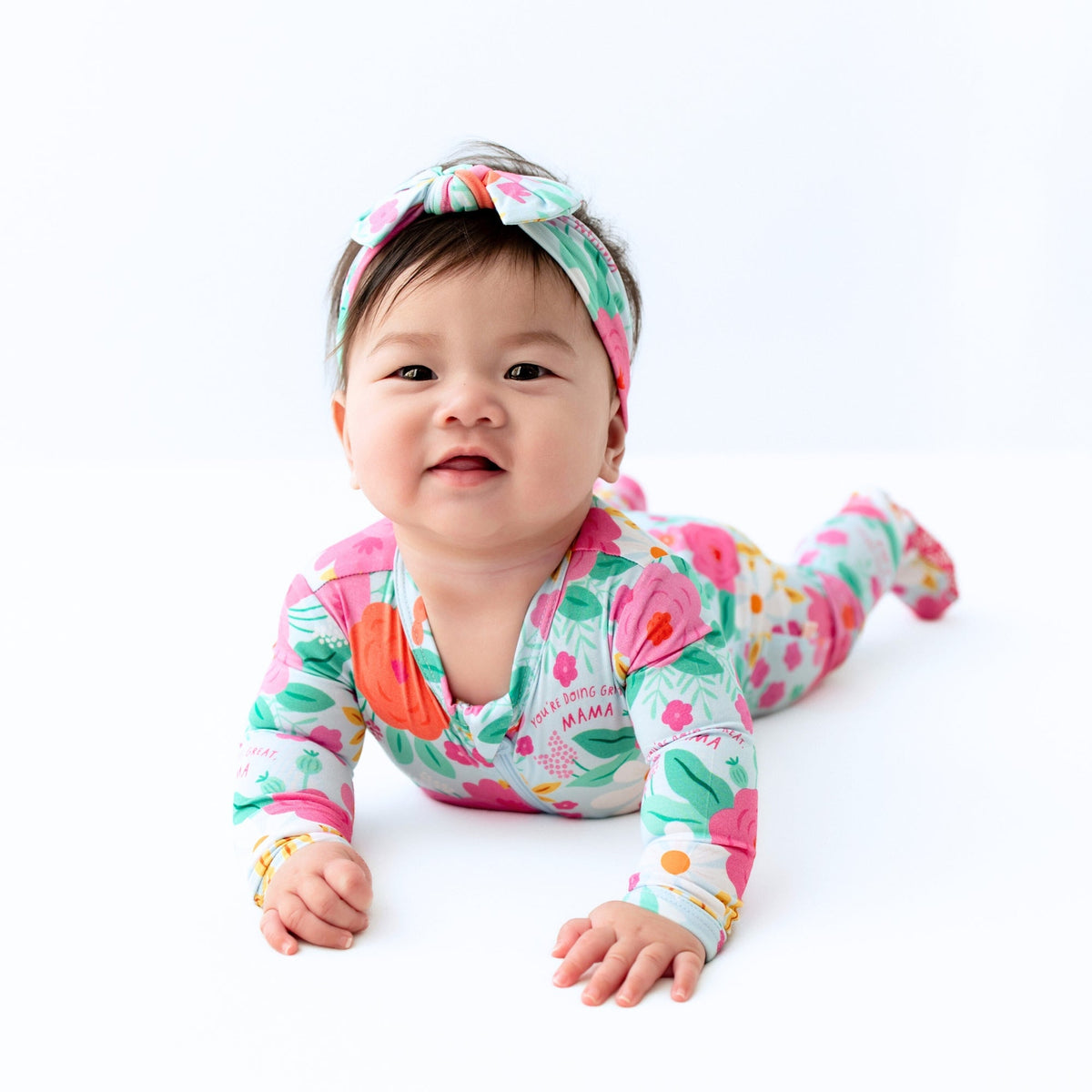The SoftKnot Baby Bow Head Wrap - Babies and Toddlers - Flower Power displayed with matching bamboo pajama prints, highlighting its coordinating style.