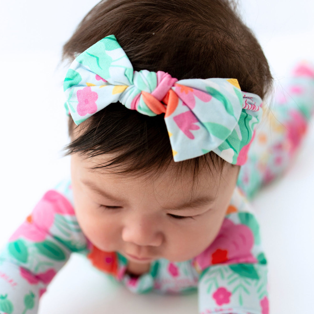 The SoftKnot Baby Bow Head Wrap - Babies and Toddlers - Flower Power being worn by a toddler, illustrating its perfect fit and style.